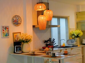 A kitchen with a coffee maker, a vase with flowers, and hanging lights. - Old Town Hideaway/Walk Everwhere/Tha Phae Gate (Chang Wat Chiang Mai)