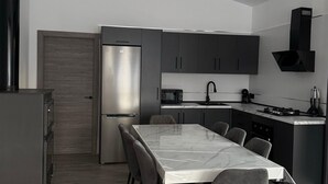 Eine moderne Küche mit einem Edelstahl-Kühlschrank, dunklen Schränken, einer Mikrowelle und einem Gasherd.
