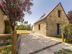 Un edificio de piedra con camino de entrada de grava y valla de madera.