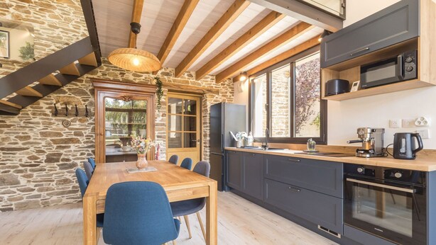 A modern kitchen with a stone wall, wooden beams, and a large window. - Cozy gîte near Nantes - max guests (Petit-Mars)