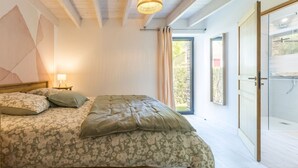A bedroom with a bed, a nightstand, a lamp, a large window, and a sliding glass door leading to an outdoor area. - Cozy gîte near Nantes - max guests (Petit-Mars)