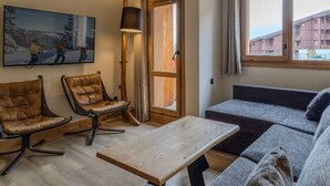 A modern living room with a sofa, two leather chairs, a wooden coffee table, a painting, a floor lamp, and a large window. - Chic apartment in Belle Plagne - 6 guests (Belle Plagne)