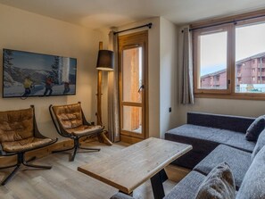 A modern living room with a sofa, two leather chairs, a wooden coffee table, a painting, a floor lamp, and a large window. - Chic apartment in Belle Plagne - 6 guests (Belle Plagne)