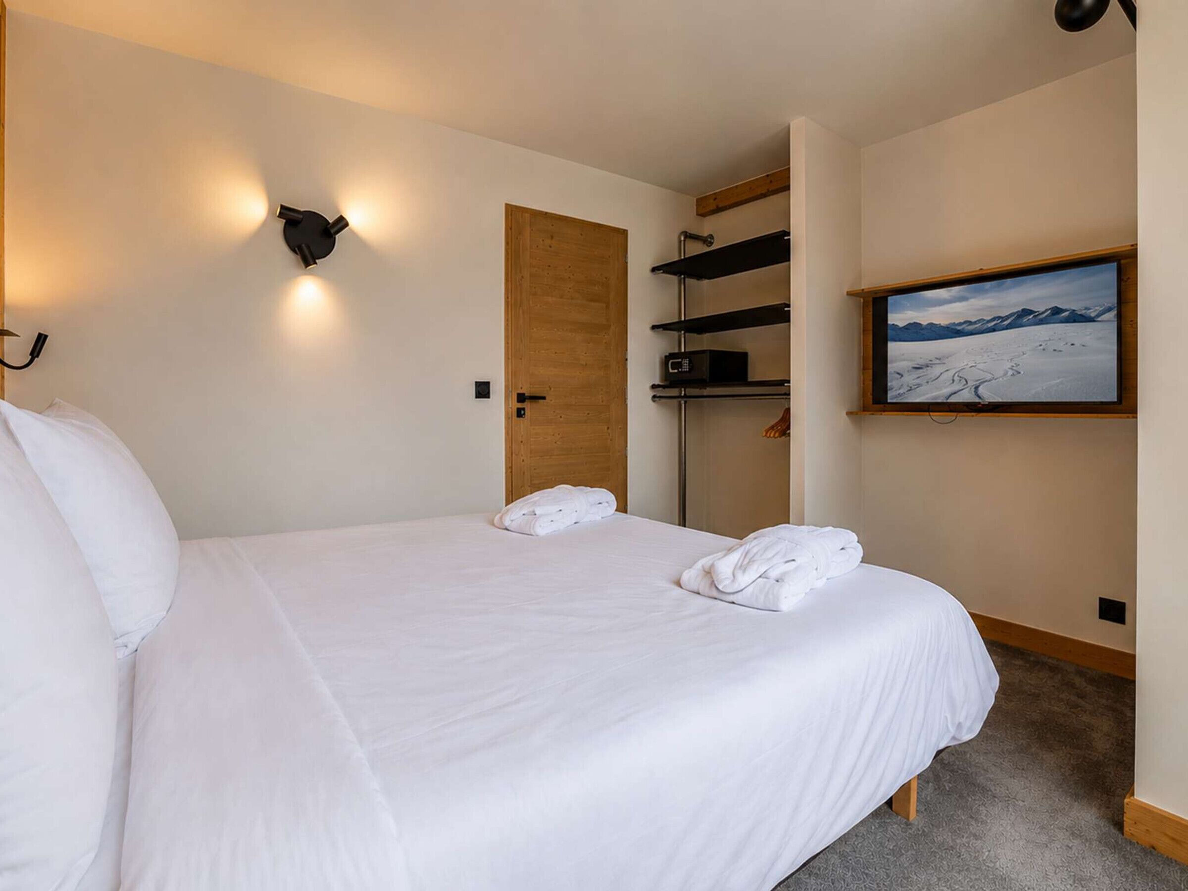 Ein Hotelzimmer mit Bett, einer Holztür, einem Fernseher und Blick auf die Berge.