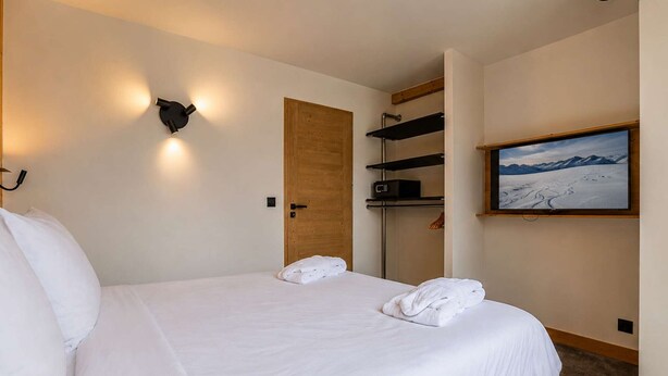 A hotel room with a bed, a wooden door, a TV, and a mountain view. - Chic apartment in Belle Plagne - 6 guests (Belle Plagne)