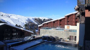 A hotel with a pool, snow-covered surroundings, and a mountainous backdrop. - Chic apartment in Belle Plagne - 6 guests (Belle Plagne)