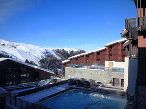 A hotel with a pool, snow-covered surroundings, and a mountainous backdrop. - Chic apartment in Belle Plagne - 6 guests (Belle Plagne)