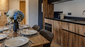 A modern kitchen with wooden cabinetry, a built-in oven, and a black countertop. - Chic apartment in Belle Plagne - 6 guests (Belle Plagne)