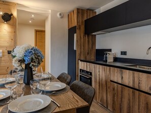 A modern kitchen with wooden cabinetry, a built-in oven, and a black countertop. - Chic apartment in Belle Plagne - 6 guests (Belle Plagne)