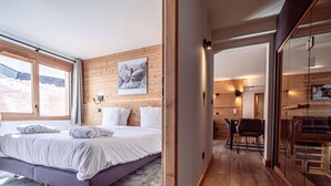 A bedroom with a large bed, a wooden wall, a painting, and a view of the outdoors. - Luxury apartment in center - 6 guests (Belle Plagne)