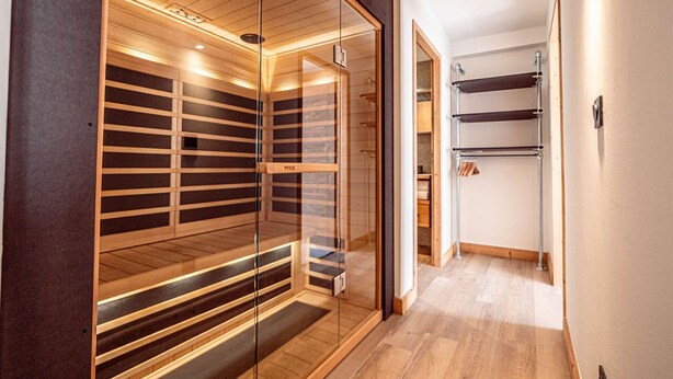 A modern interior with a glass partitioned sauna area, wooden flooring, and a metal rack on the wall. - Luxury apartment in center - 6 guests (Belle Plagne)