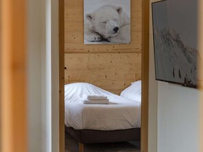 Un dormitorio con cabecera de madera, cama con ropa de cama blanca y un cuadro enmarcado de un oso polar en la pared.