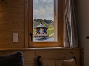 A wooden cabin with a window overlooking a small building with two clocks. - Luxury apartment, prime location - 8 guests (Belle Plagne)