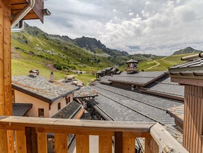 Una cabaña tradicional con terraza de madera, tejado de piedra y vistas a un paisaje montañoso.