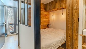 Una camera da letto con un letto, pannelli in legno e vista panoramica attraverso una porta vetrata.