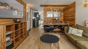 Un soggiorno moderno con pavimento in legno, un divano, un tavolo da pranzo apparecchiato per quattro persone e una cucina sullo sfondo.