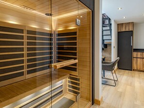 Eine moderne Küche mit Holzschränken, einem eingebauten Herd und einem Essbereich mit einem Stuhl.