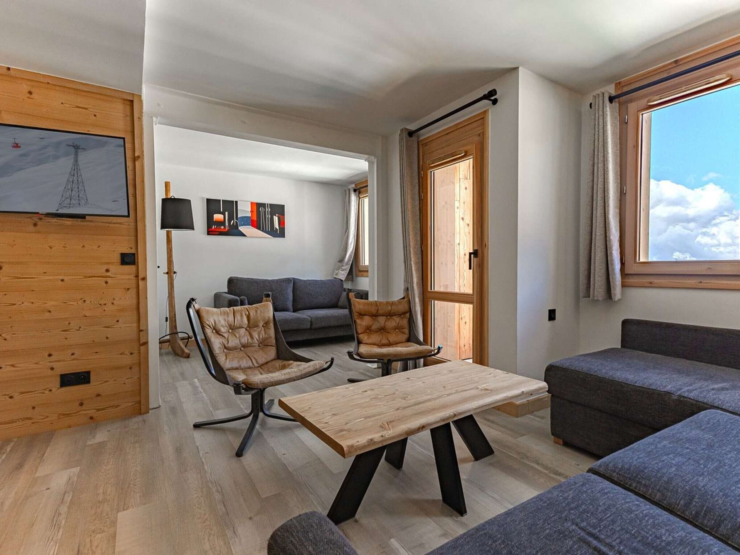 A modern living room with a sofa, two armchairs, a wooden coffee table, and a grey couch.