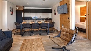 Et moderne interiør med et spiseområde, en sofa og et fjernsyn monteret på væggen.