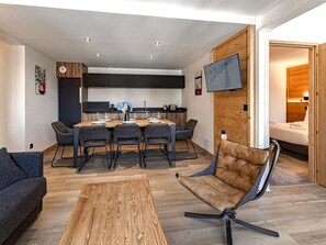 A modern interior with a dining area, a sofa, and a TV mounted on the wall. - Spacious apartment, 8-10 guests, in Belle Plagne (Belle Plagne)
