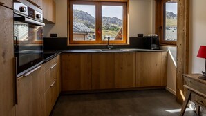 Una cucina con mobili in legno, un lavello doppio e una finestra con vista sulle montagne.