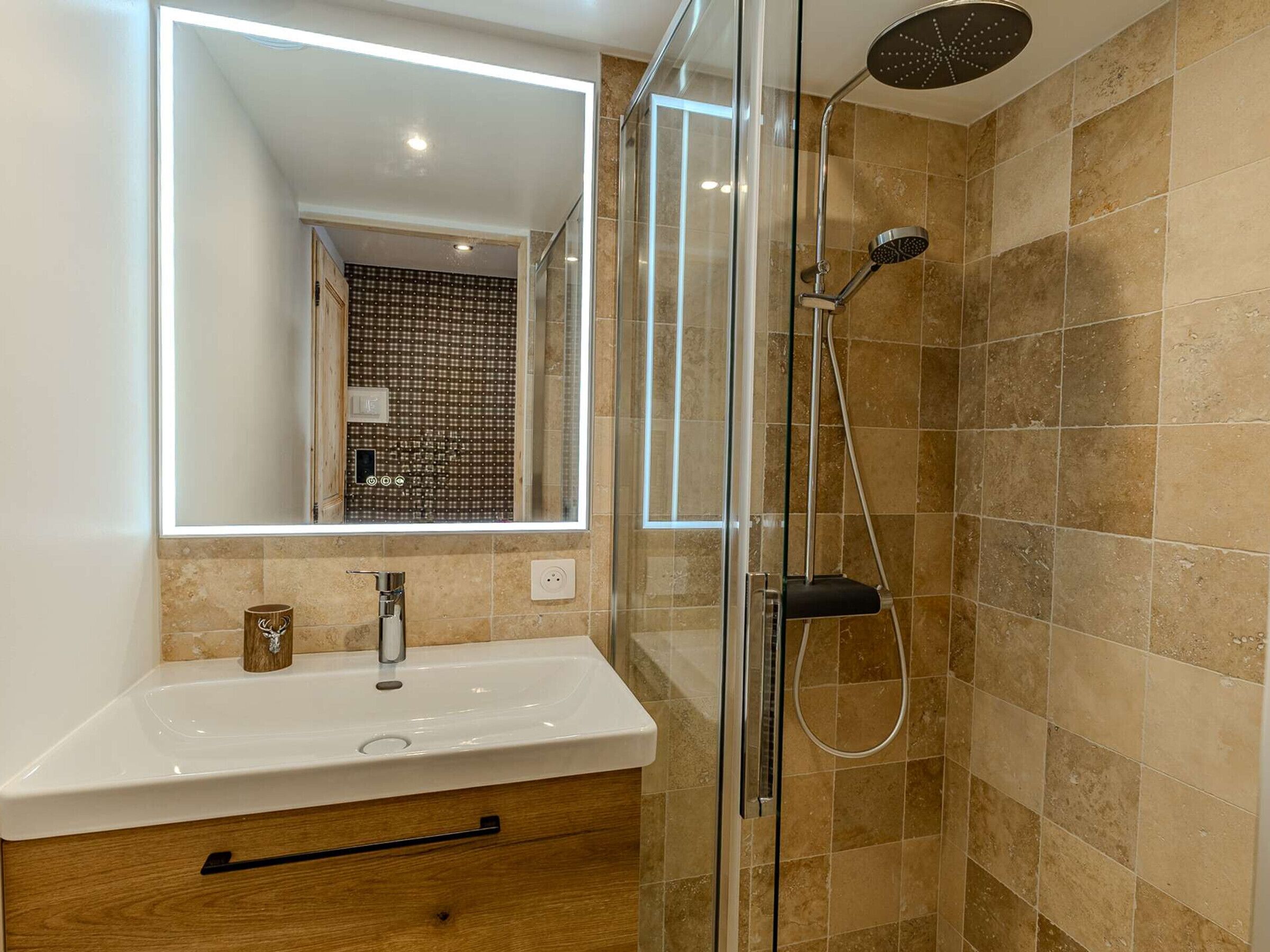 A modern bathroom with a glass-enclosed shower, a white sink, and a mirror reflecting the room.