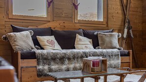 L'interno accogliente di una baita, con un divano di legno, un tavolino da caffè in vetro e un tappeto bianco e soffice.