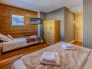 A room with two beds, wooden walls, a large wardrobe, and a television. - Modern mountain chalet - 9 guests (Plagne Soleil)
