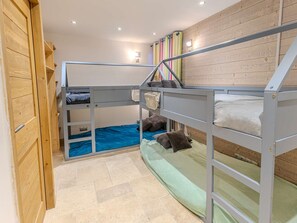 Une chambre avec un lit superposé, un mur en bois, une petite fenêtre et un luminaire.