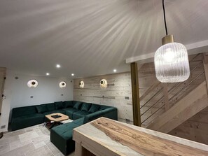 Ein modernes Wohnzimmer mit einem Ecksofa, einem Holztisch und einer Treppe.