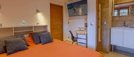 Un dormitorio moderno con cama, escritorio y baño.