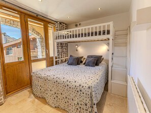 Ein Schlafzimmer mit einem Etagenbett, einem großen Fenster und Blick auf ein Steinhaus.