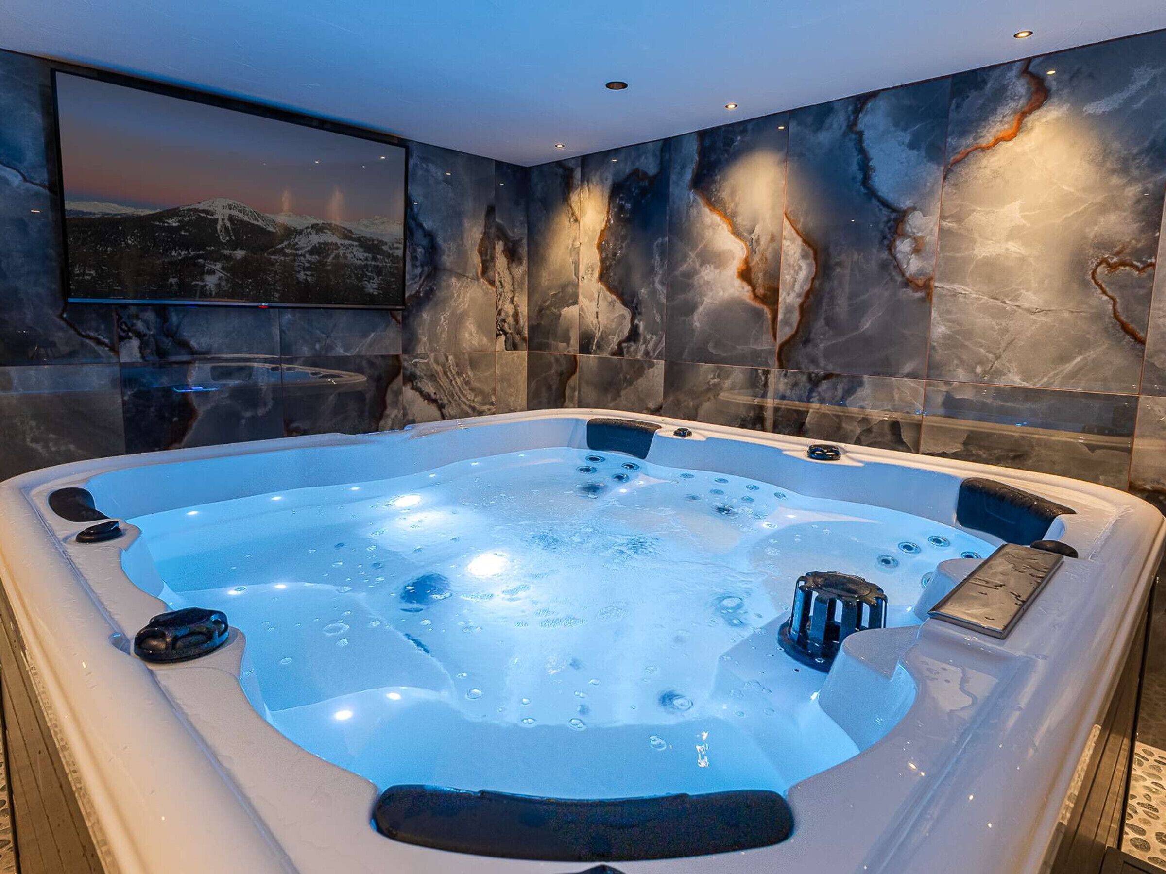 A hot tub with a view of a mountainous landscape through a large window.