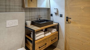 A bathroom with a wooden vanity, a large mirror, a sink, and a towel rack. - Cozy apartment - 6 guests, near slopes (Belle Plagne)