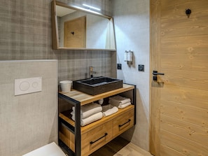 A bathroom with a wooden vanity, a large mirror, a sink, and a towel rack. - Cozy apartment - 6 guests, near slopes (Belle Plagne)