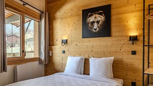 Habitació amb panells de fusta, un llit, dues làmpades fixades a la paret i una obra d'art amb tema d'ós.