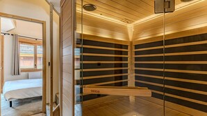 Habitació moderna amb llit, separador de vidre i sostre de fusta.