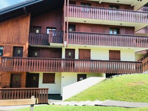A multi-story wooden building with balconies and a staircase leading to the upper floors. - Apartment with mountain view, pets welcome - 4 guests (Morillon Village)