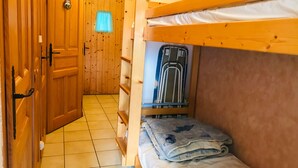 A bunk bed room with wooden walls, a door, and a window with a curtain. - Apartment with mountain view, pets welcome - 4 guests (Morillon Village)