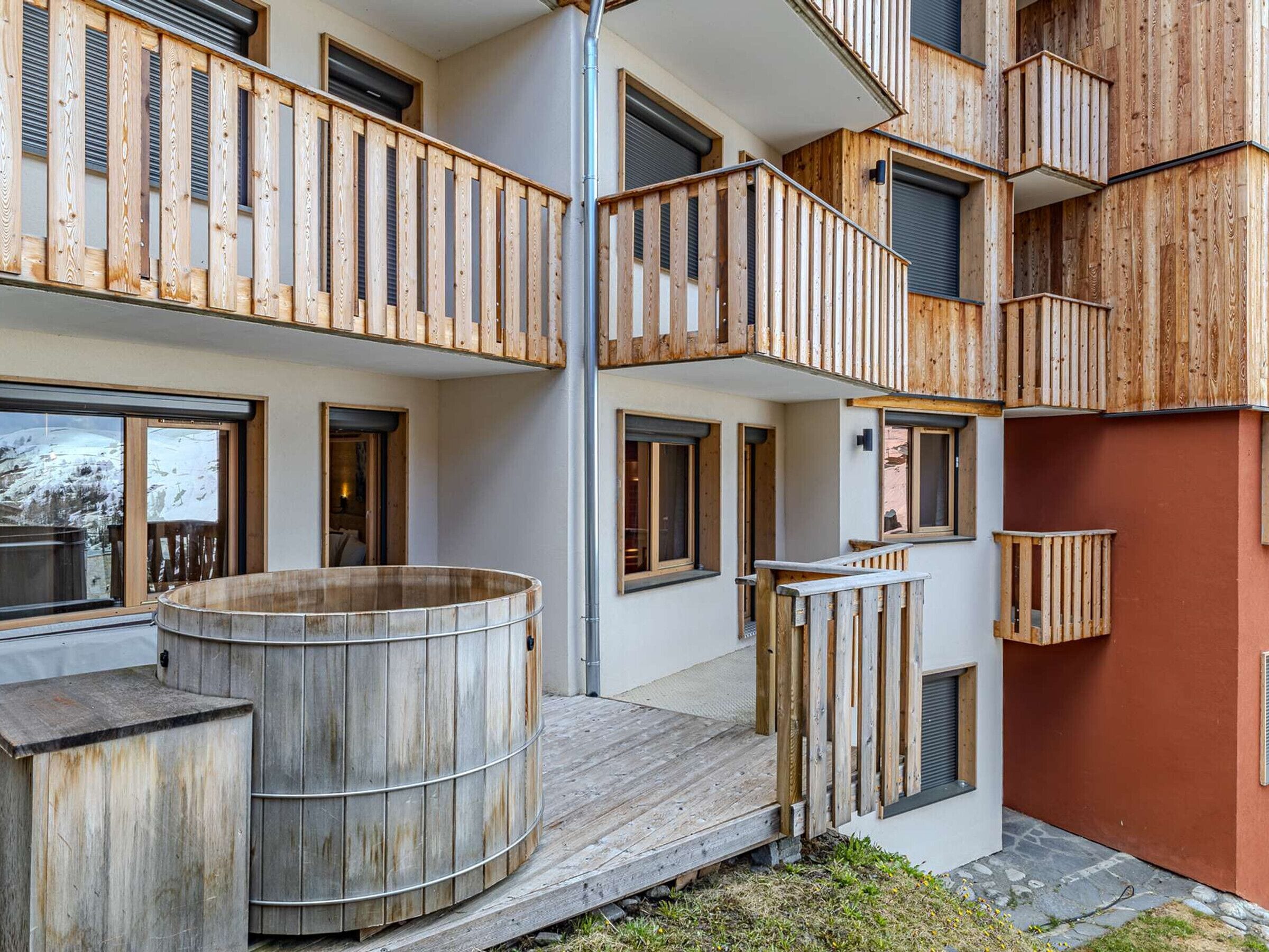 A multi-story building with wooden balconies, large windows, and a central wooden structure.