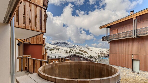 A wooden hot tub with a wooden deck, a mountain view, and a building with a wooden facade. - Cozy apartment in Belle Plagne - 6 guests (Belle Plagne)