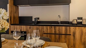A modern kitchen with wooden cabinetry, a black countertop, a stainless steel sink, and a coffee maker. - Cozy apartment in Belle Plagne - 6 guests (Belle Plagne)