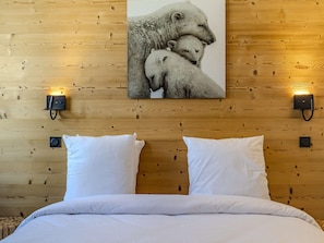 Eine Holzwand mit einem Bild von Eisbären, zwei weißen Kissen und zwei Wandleuchten.