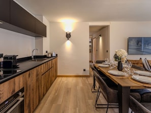 Eine moderne Küche mit einer Holzinsel, einem Essbereich mit Holztisch und -stühlen sowie einer wandmontierten Leuchte.