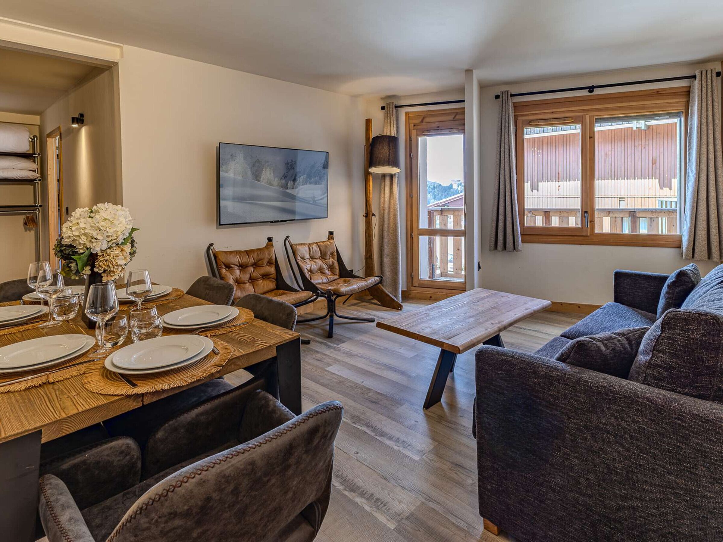 Un coin repas avec une table en bois dressée pour quatre personnes, entourée de chaises rembourrées.
