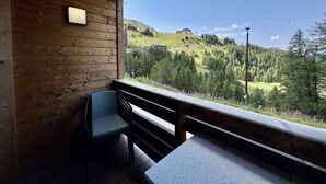 En træhytte med balkon med udsigt over et bjerglandskab.