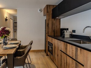 Eine moderne Küche mit Holzausstattung, einer schwarzen Arbeitsplatte und einem Edelstahlspülbecken.