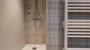 Een moderne badkamer met een douche, een handdoekhouder en een structuurwand.