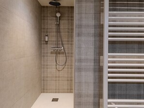 Ein modernes Badezimmer mit Dusche, Handtuchhalter und einer strukturierten Wand.