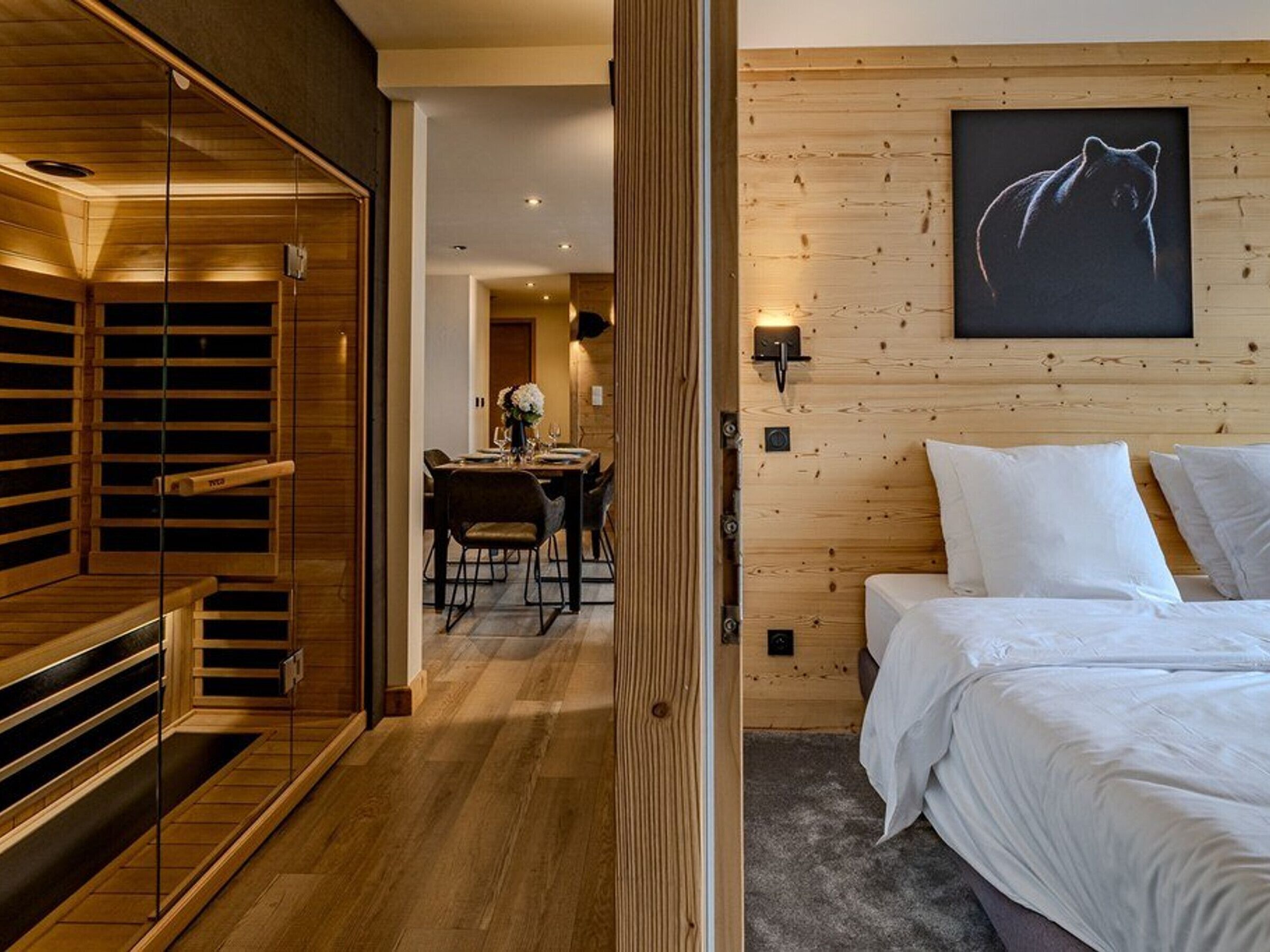 Une pièce comprenant un lit, un mur en bois, un coin repas et un espace sauna.